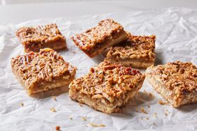 Six pecan pie bars on a crumbled piece of white parchment paper