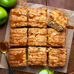 Caramel Apple Snack Cake on a piece of parchment on a wooden table and cut into pieces.