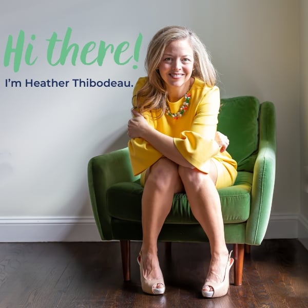 heathered nest owner, heather thibodeau wearing yellow dress seated in green velvet chair. text overlay, hey, hey, hey i'm heather